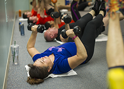 Woman participating in a fitness class with free weights.