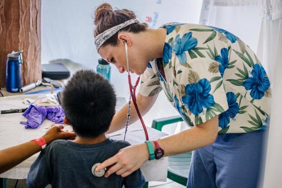 A doctor uses a stethoscope to listen to the chest of young boy