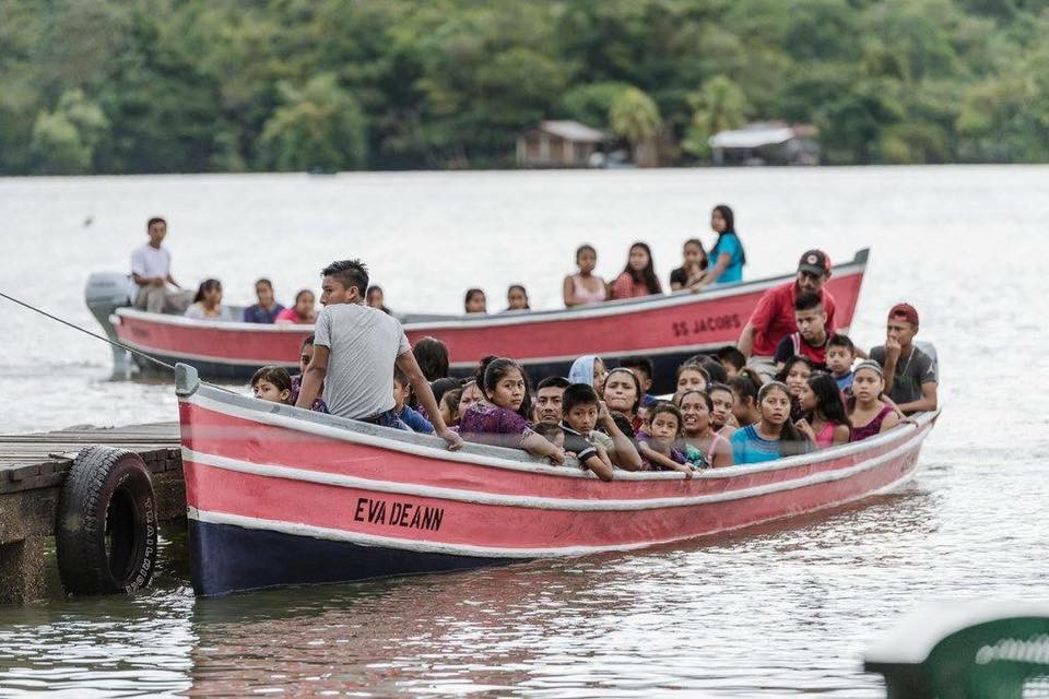 Two small boats full of people approach a dock