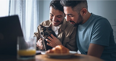 Two people sitting while holding a cat