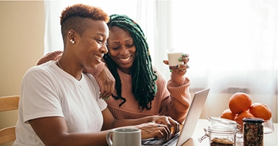 Two people siting in front of a computer smiling